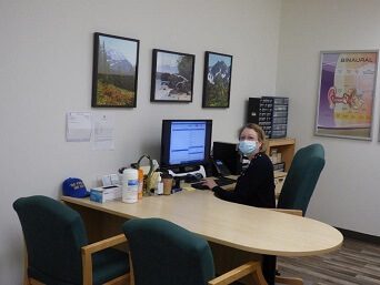 Julie VanAusdal sitting at desk wearing mask